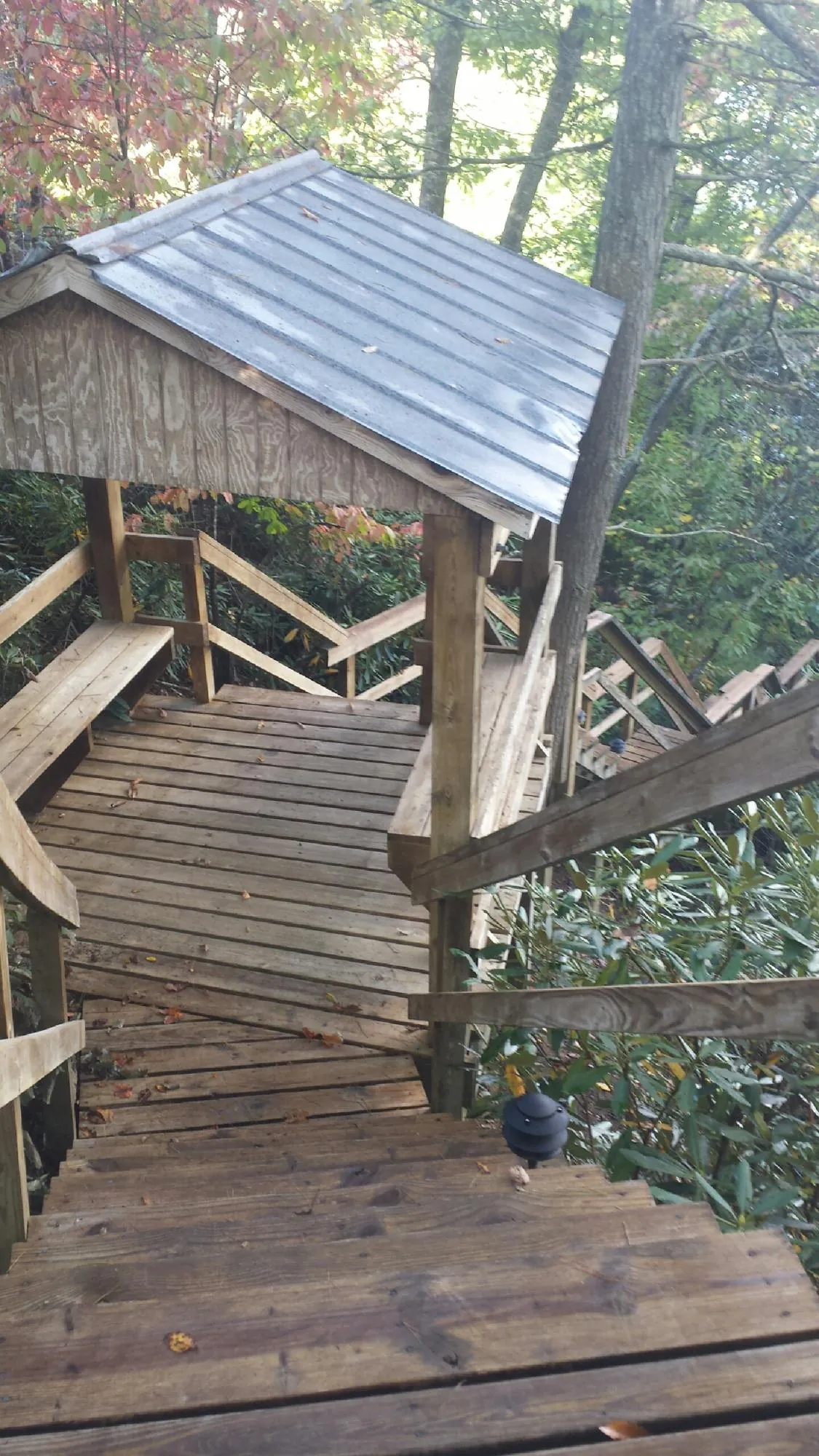 Metal roofed shelter over wooden steps on a wooded walkway — Skylight Repair & Installation work by our crew in Breezewood