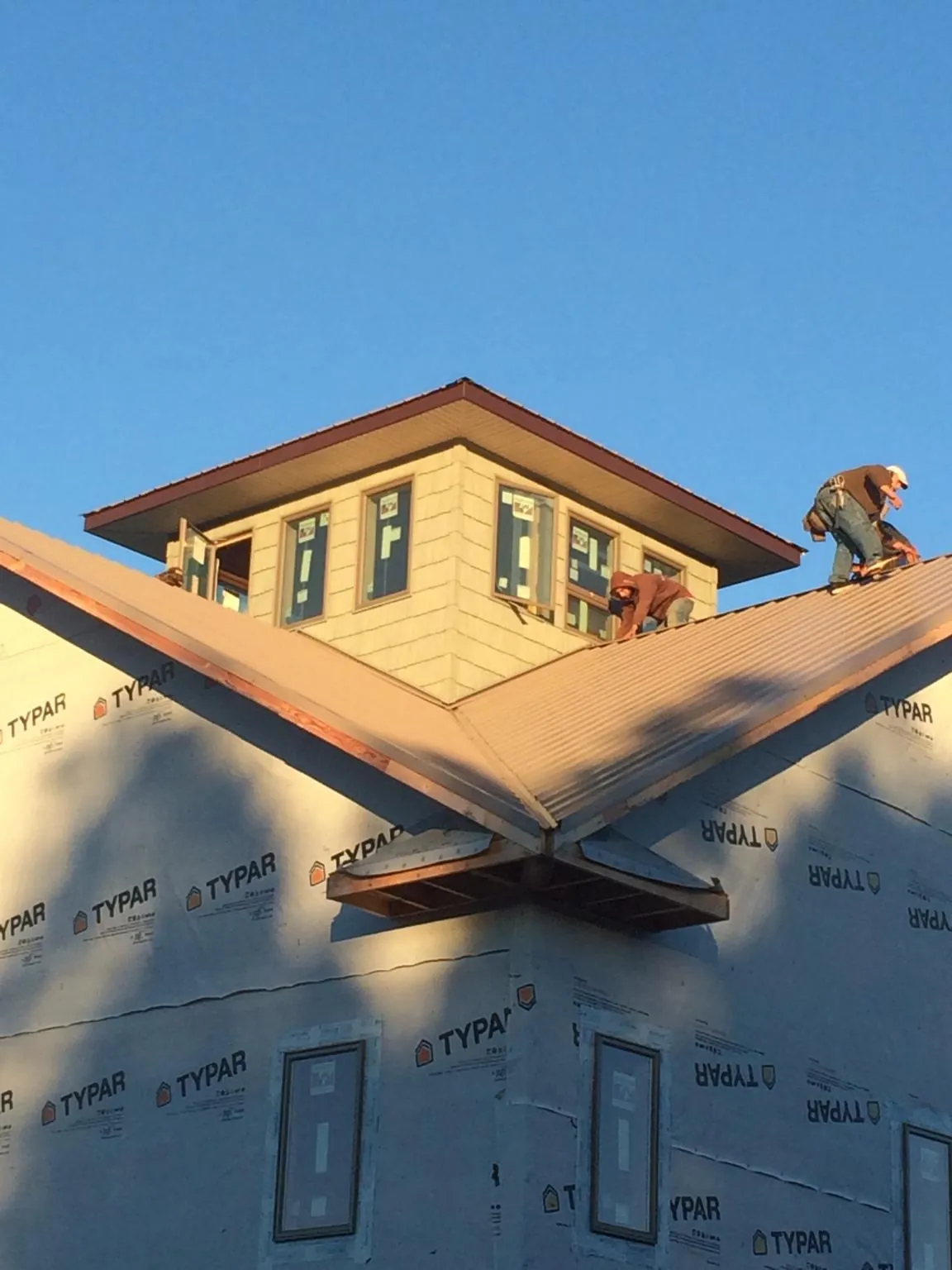 Roofers working around a rooftop cupola on a new metal roof at sunset — Roof Waterproofing in Breezewood by Roofing Brothers